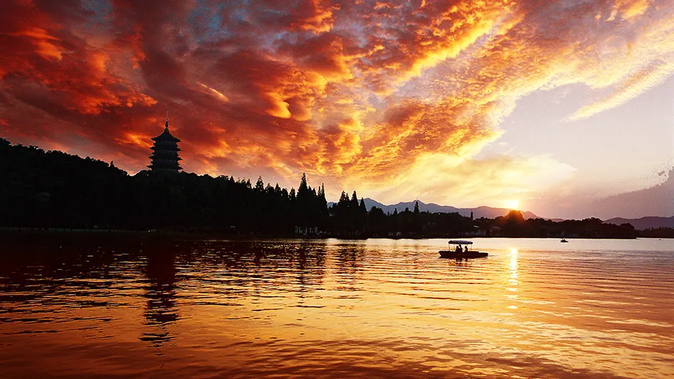Leifeng Pagoda silhouetted against a glowing sunset over West Lake