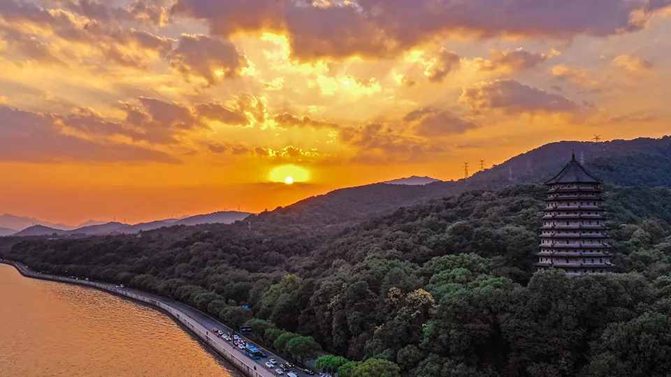 Liuhe Pagoda rises from a wooded hillside beside the broad Qiantang River at sunset